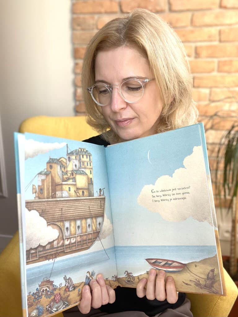 A woman is reading a book about a ship. dla dzieci