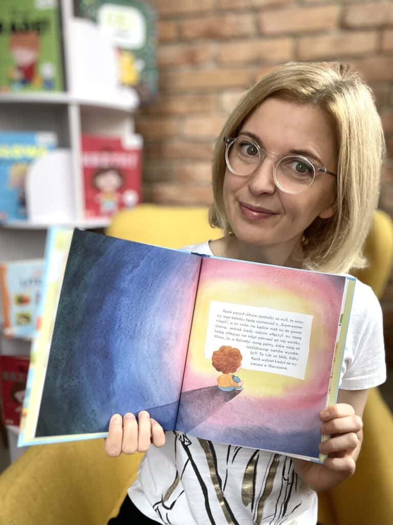 Kobieta trzymająca otwartą książkę dla dzieci, promująca aktywne czytanie.