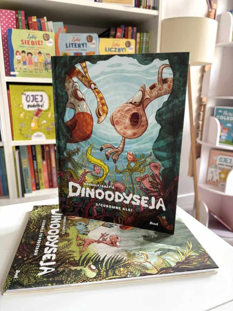 Okładka komiksu „Dinoodyseja 3. Cudowne algi” z dwoma dinozaurami o długich szyjach pod wodą, na tle zielonych roślin morskich, leżąca obok drugiej części serii Wait, I need to check the rules: no ending period, under 120 characters, not starting wit