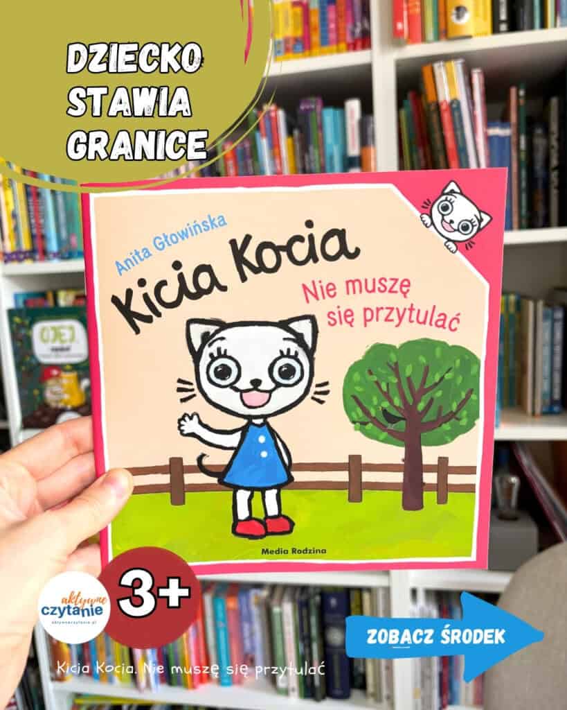Ręka trzyma książkę „Kicia Kocia. Nie muszę się przytulać” Anity Głowińskiej, na której okładce biała kotka w niebieskiej sukience machа do czytelnika obok zielonego drzewa Wait, I need to correct the typo and check the rules: no period at end, under